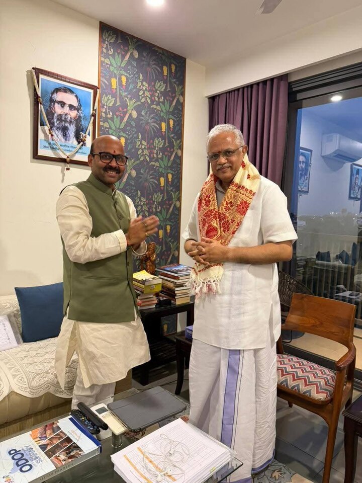 Harish Dwivedi greeting a senior citizen with folded hands during a meeting