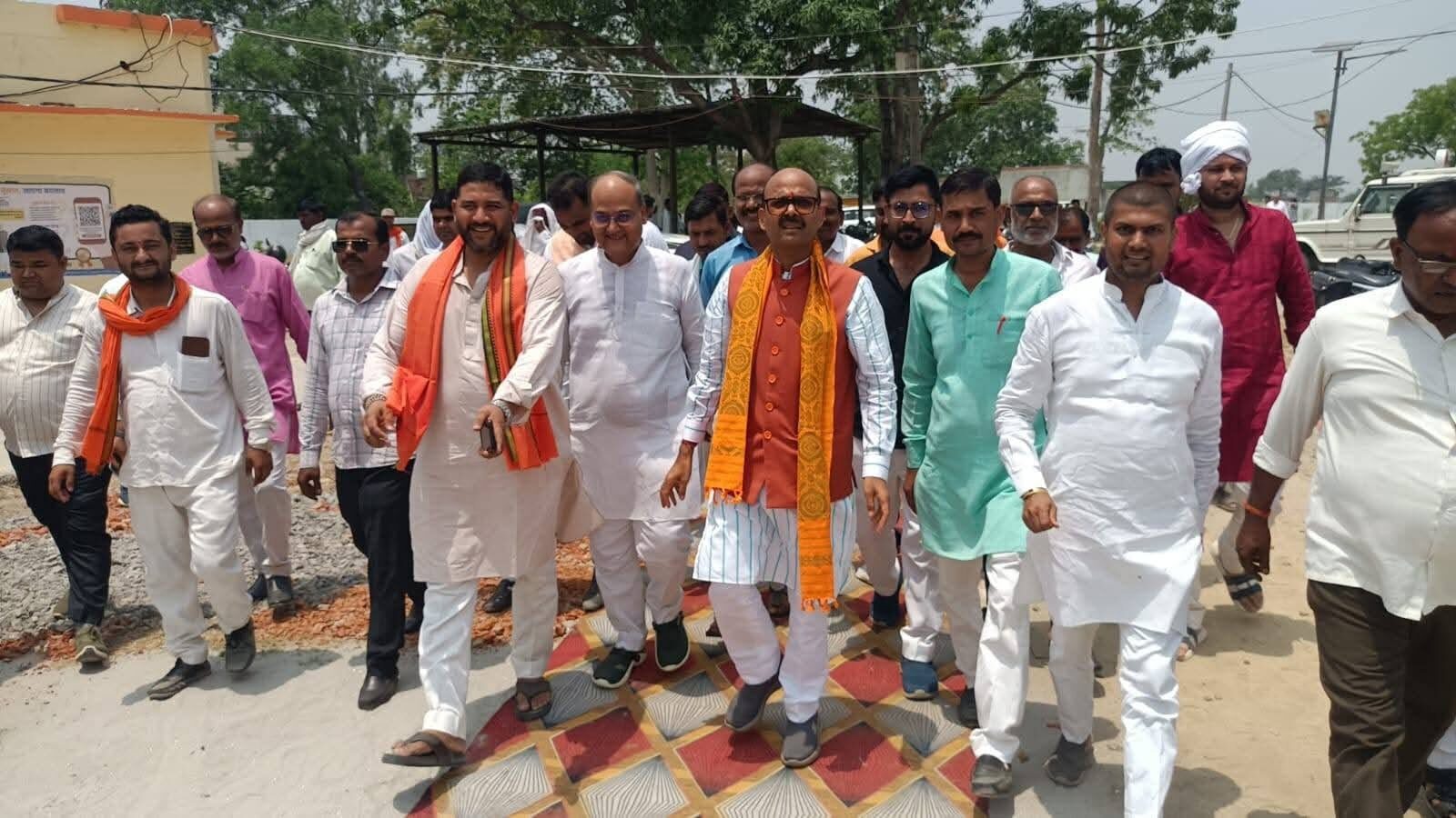 Harish Dwivedi walking along a village road accompanied by residents and local representatives