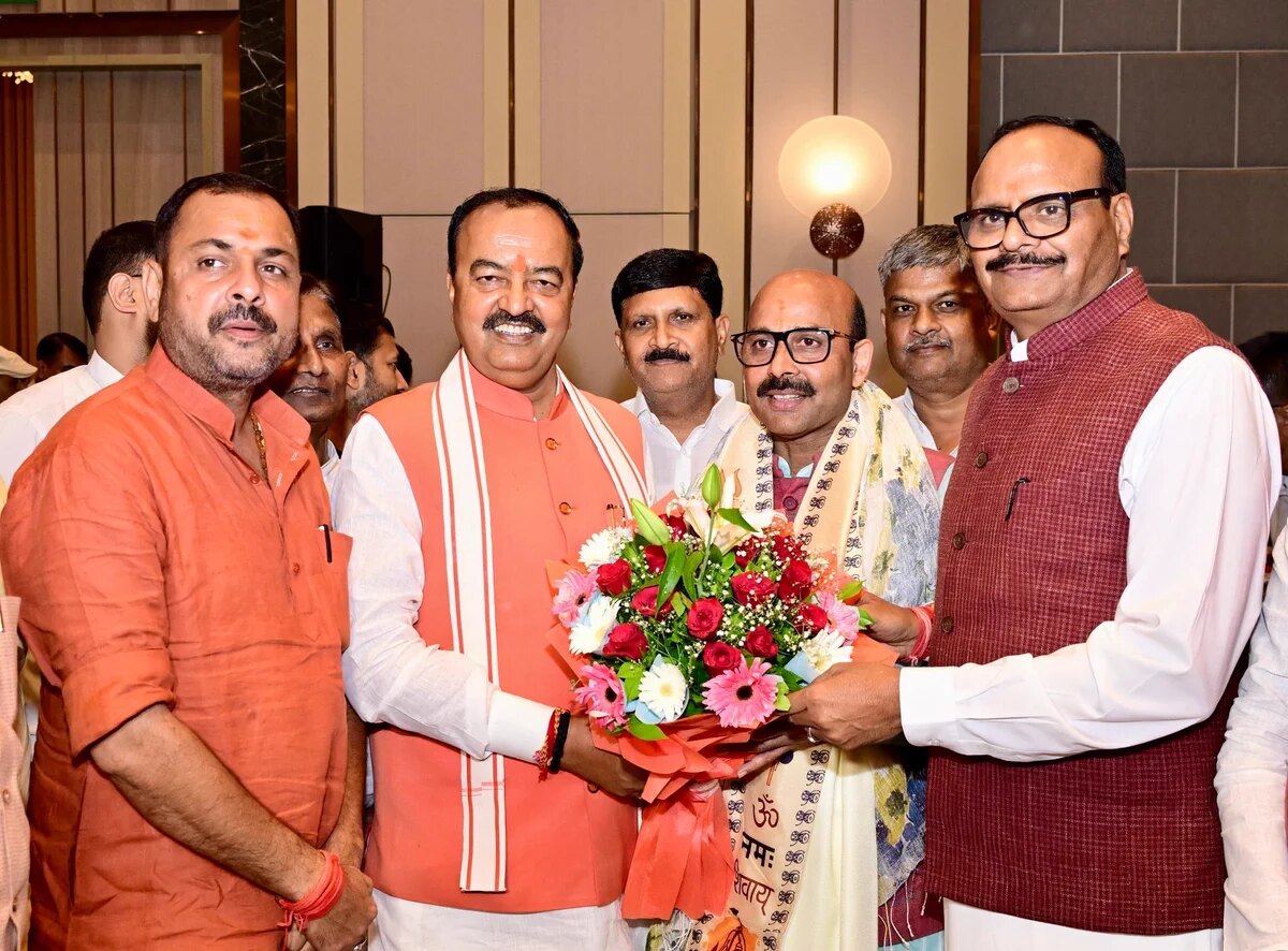 Harish Dwivedi receiving a bouquet of flowers at an official function alongside colleagues