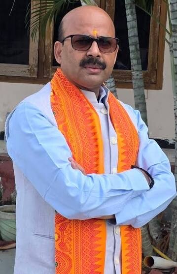 Harish Dwivedi standing outdoors wearing sunglasses and a traditional stole