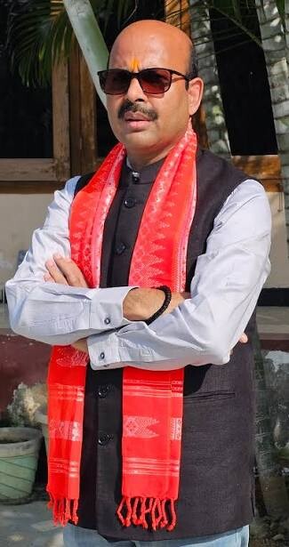 Harish Dwivedi standing outdoors wearing a red and white traditional Assamese gamosa