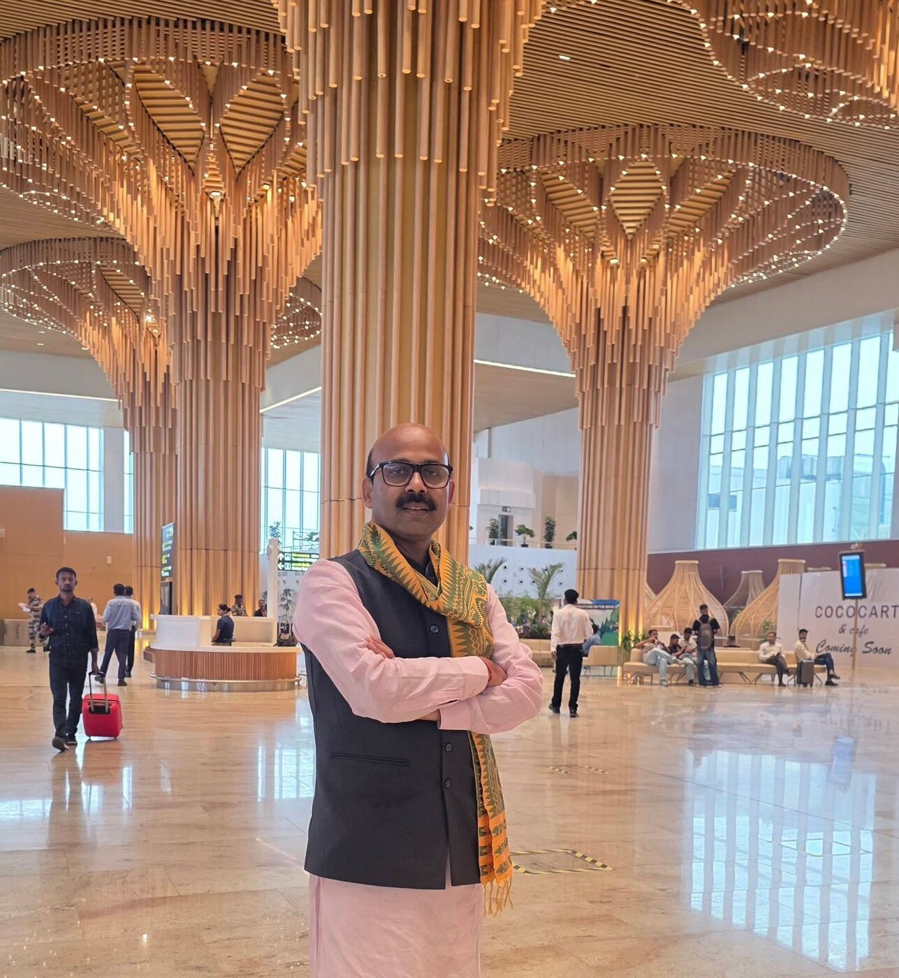 Harish Dwivedi standing in a modern airport terminal concourse with timber column architecture