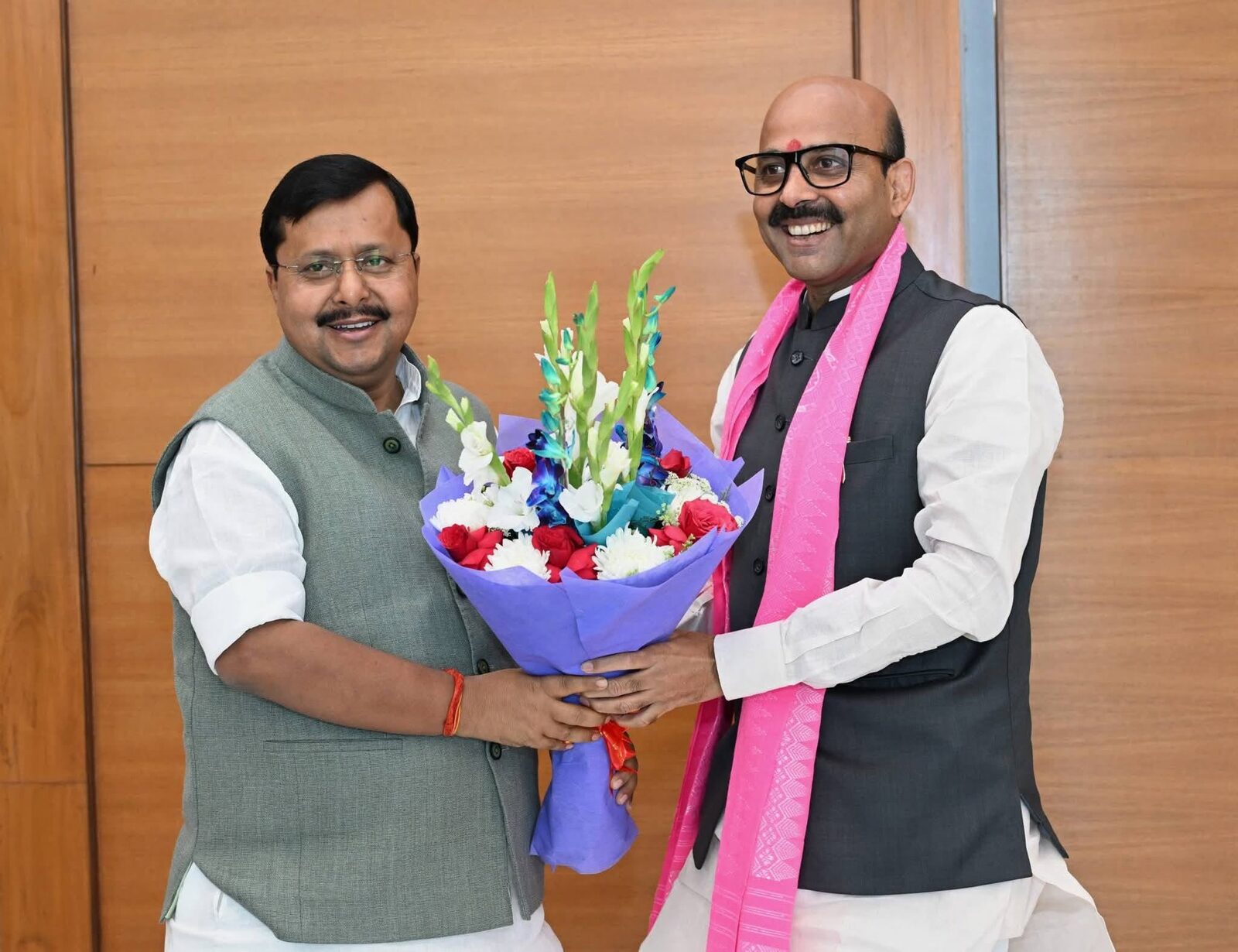 Harish Dwivedi being welcomed with a bouquet of flowers on arrival at an indoor venue