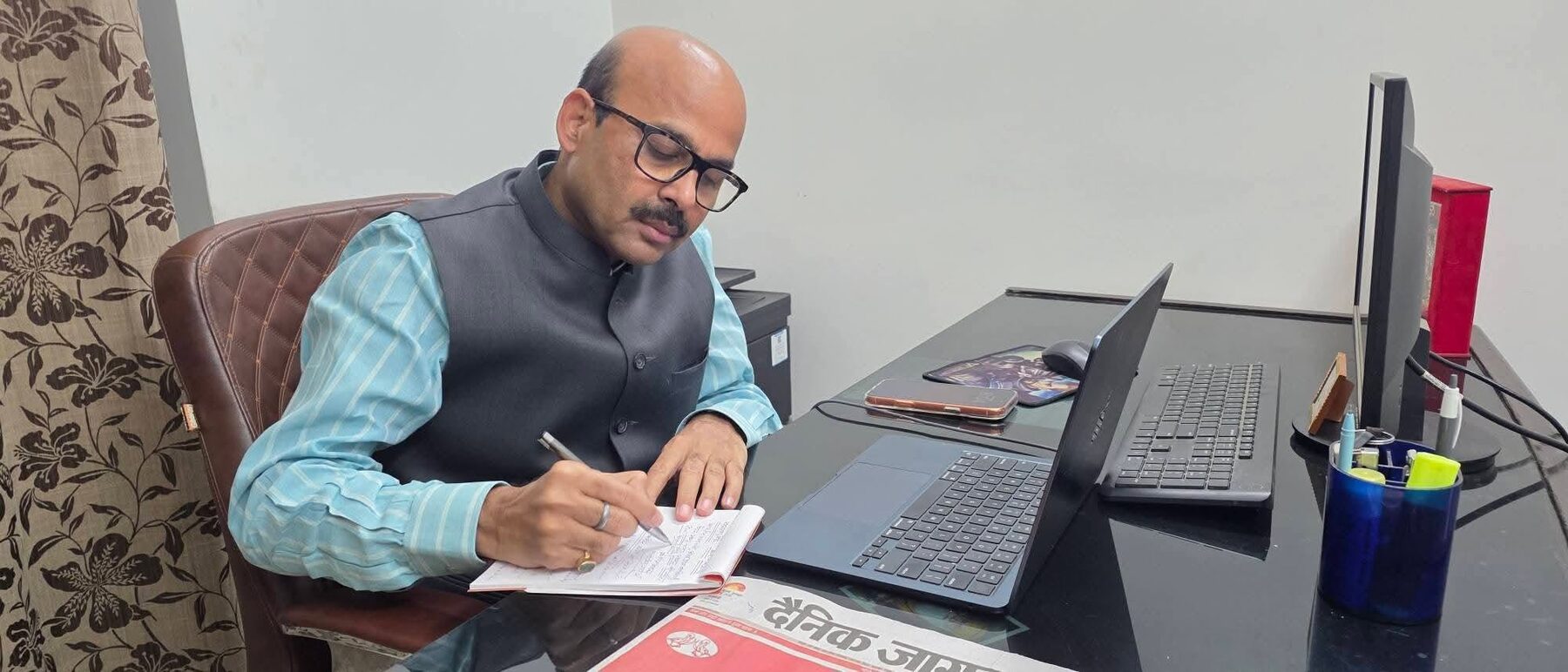 Harish Dwivedi working at his desk, reviewing and signing papers