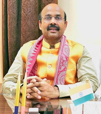 Harish Dwivedi seated at a desk with the national flag beside him