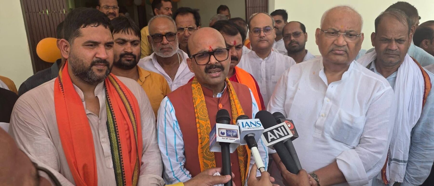 Harish Dwivedi speaking to journalists holding news agency microphones